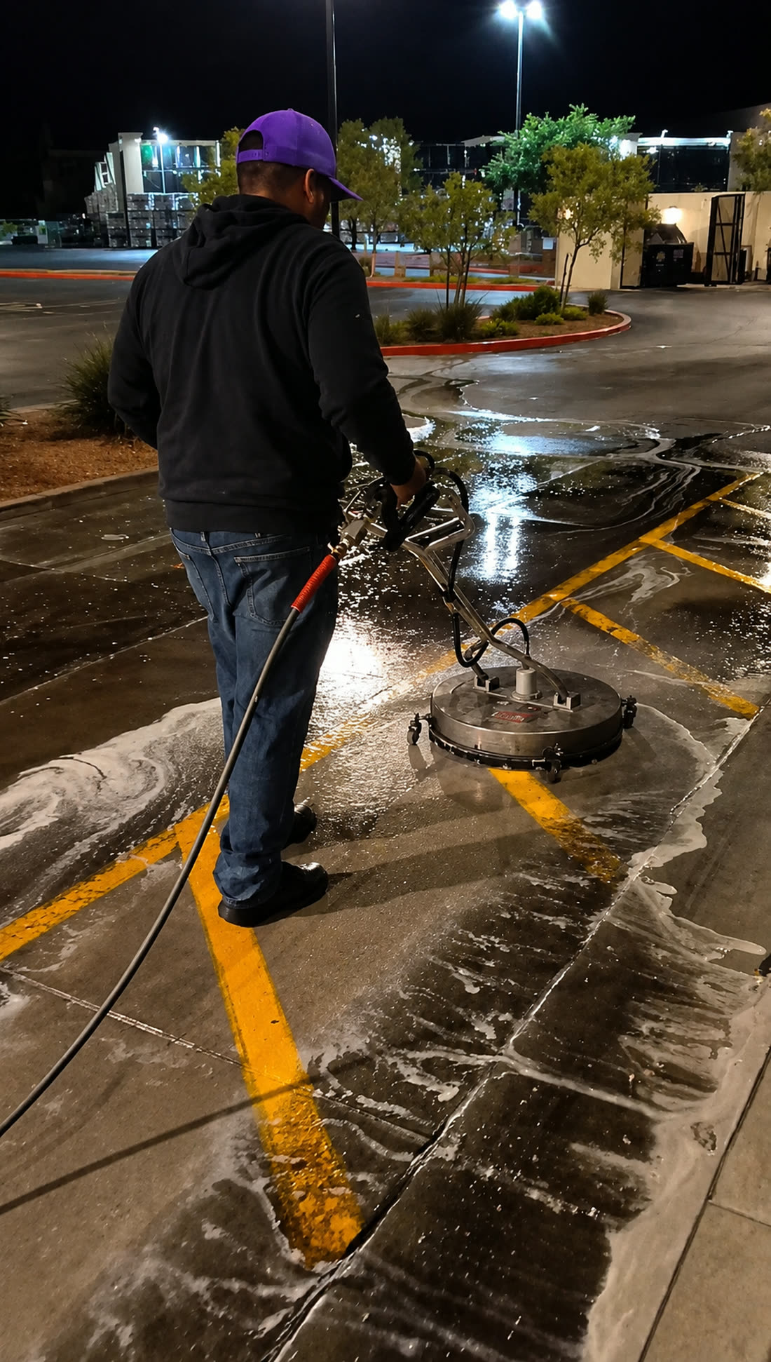 LVC technician using a surface cleaner on a commercial parking lot at night